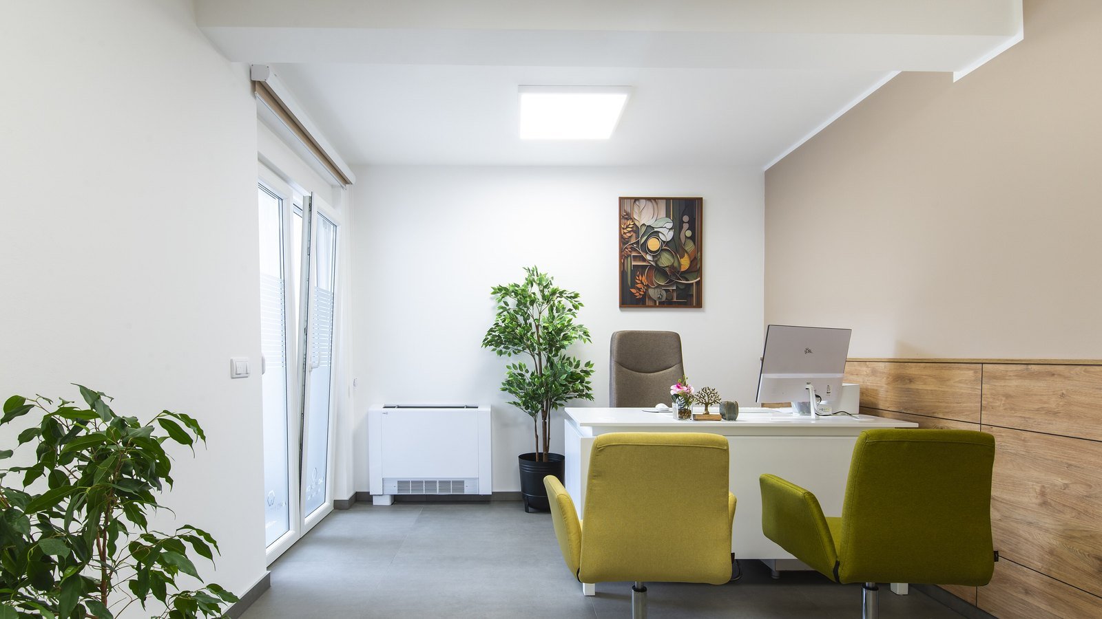 A bright, modern office space with a white desk, two mustard chairs and potted plants