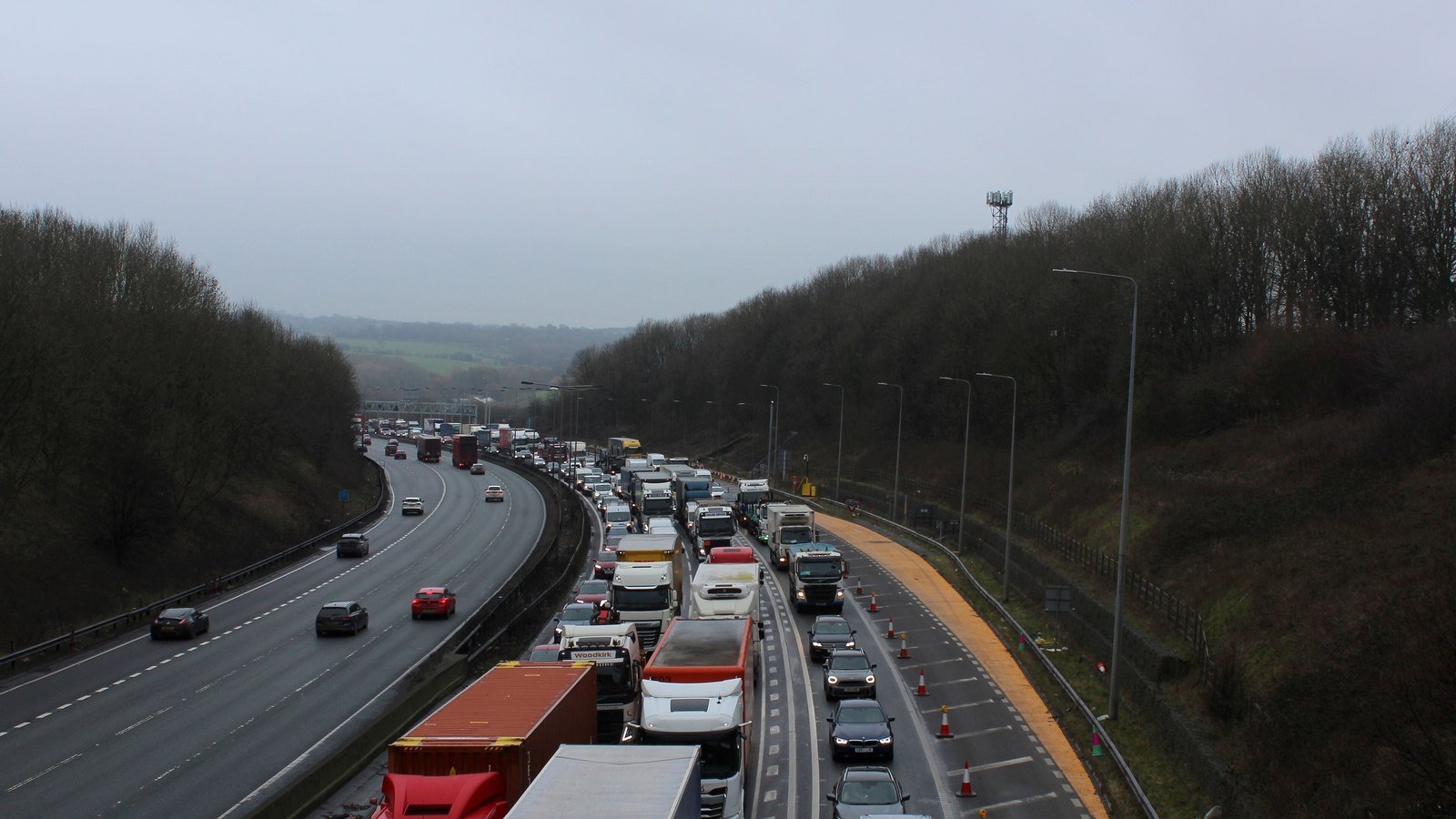 Lorries and cars queuing in heavy traffic on a motorway, with the opposite carriageway clear